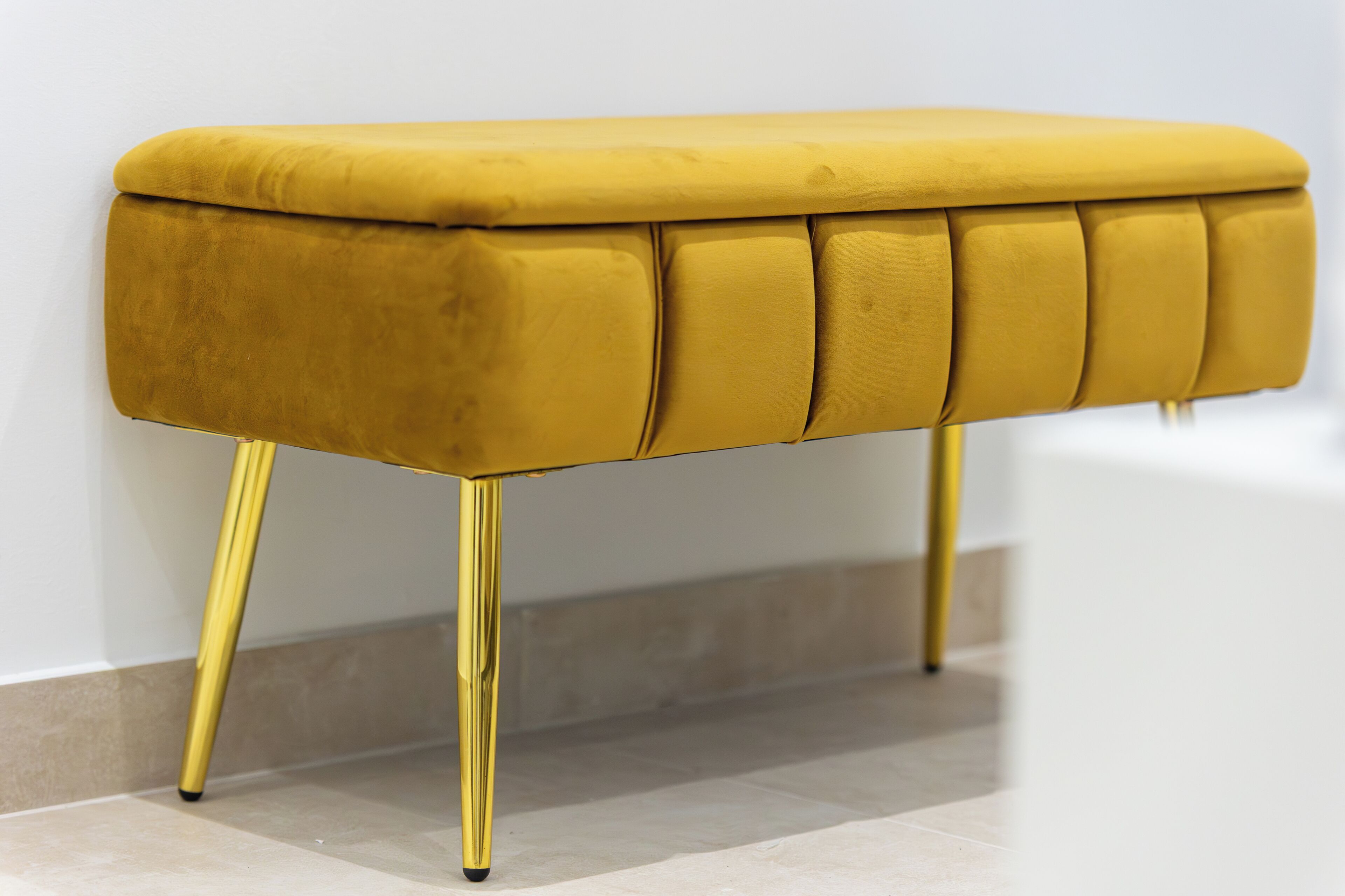 Un banc recouvert d’un tissu jaune, avec des pieds dorés.