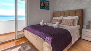 Ein Schlafzimmer mit einem Bett, einem Nachttisch, einem Gemälde und Meerblick.
