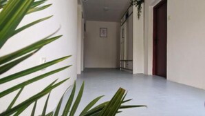 A hallway with a white floor, a door on the right, and a plant on the left. - Three Bedroom Apartment With Balcony And Sea View (Karlobag)