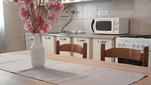Eine Küche mit einem Holztisch, Stühlen, einer weißen Mikrowelle und einem Herd.