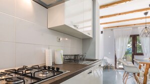 Eine moderne Küche mit Gaskochfeld, weißen Schränken und einem Essbereich mit Tisch und Stühlen.
