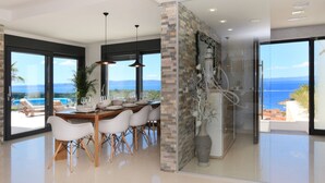 A modern dining area with a view of the ocean, a glass partition, and a decorative sculpture. - Lux Villa Afrodita Makarska - Three Bedoom Villa with Outdoor Pool (Makarska)