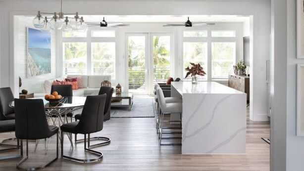 A modern kitchen with a marble island, black chairs, and a dining area with a view of the outdoors. - Swimming Pool / Boat Dock / Close to Key West (Sugarloaf)