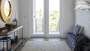 A modern living room with a large window, a round mirror, a hanging light fixture, and a decorative fish on the wall. - Swimming Pool / Boat Dock / Close to Key West (Sugarloaf)