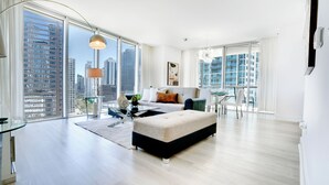 A modern living room with a large window, a sofa, a coffee table, and a dining area. - RS Suites - W Miami (Miami)
