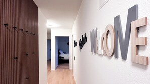 Ein Flur mit einem Holzschrank, einem Bett am Ende des Raumes und einer Wand, an der das Wort 'LOVE' mit Buchstaben angebracht ist.