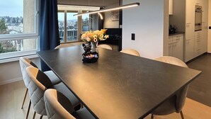 Ein moderner Essbereich mit einem langen Tisch, Stühlen und einer Blumenvase.