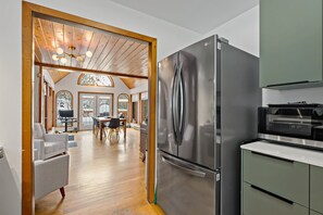 Eine moderne Küche mit einem Edelstahlkühlschrank, einem eingebauten Backofen und einem Essbereich mit einem Holztisch und Stühlen.