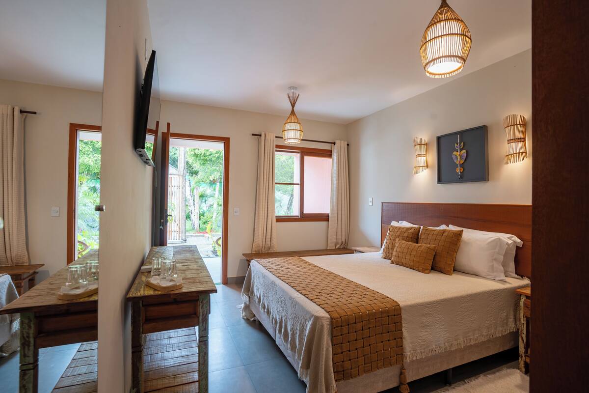 A bedroom with a bed, bedside tables, a TV, and a window with curtains.