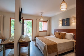 A bedroom with a bed, bedside tables, a TV, and a window with curtains. - Pousada Santa Felicidade (Porto Seguro)