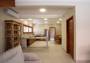 A kitchen with a dining area, a built-in oven, and a refrigerator. - Pousada Santa Felicidade (Porto Seguro)