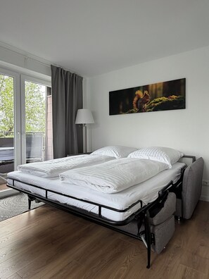 Ein Schlafzimmer mit Bett, Fenster, Lampe und einem Bild.