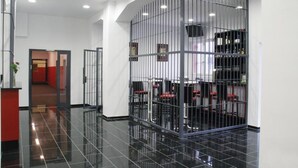 A modern hotel lobby with a polished black floor, a reception desk, and a seating area enclosed by metal bars. - ALCATRAZ Hotel am Japanischen Garten (Kaiserslautern)