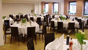 A banquet hall with multiple round tables, each set with white tablecloths, chairs, and centerpieces. - ALCATRAZ Hotel am Japanischen Garten (Kaiserslautern)