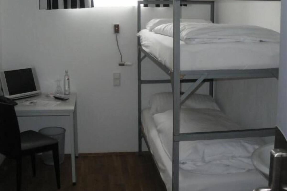 Un dormitorio tipo camarote con escritorio, silla y laptop.