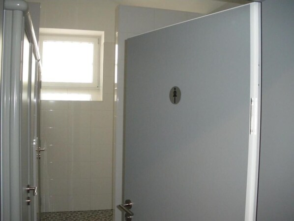 A closed door with a window above it, a tiled floor, and a metal handle. - ALCATRAZ Hotel am Japanischen Garten (Kaiserslautern)