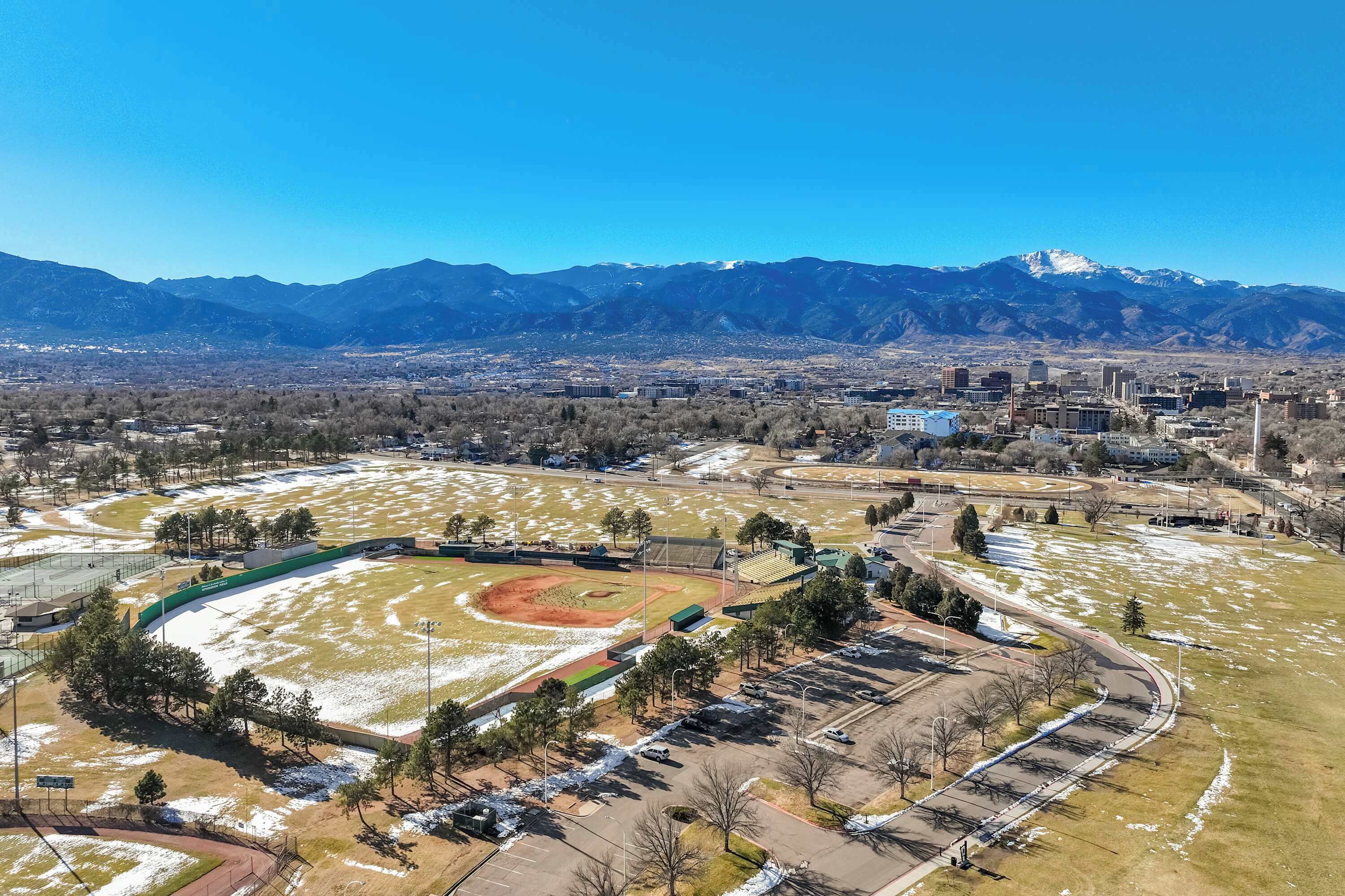 An aerial view of a baseball field with surrounding buildings and mountains in the background.