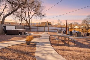 Un patio trasero con terraza, mobiliario exterior y un jacuzzi.