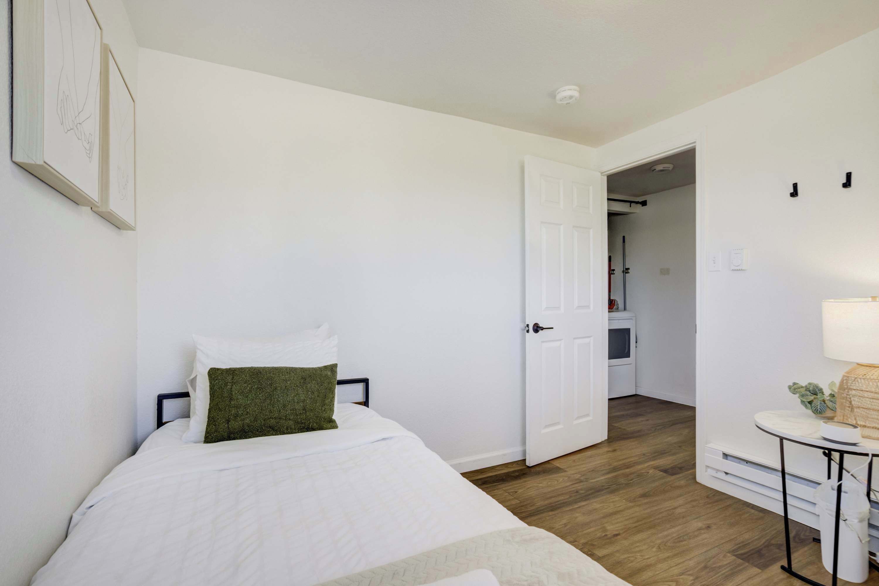 Une chambre à coucher avec un lit, une porte donnant sur une salle de bain et une petite table avec une lampe.