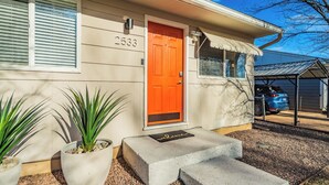 Ein Haus mit der Nummer 2533 an der Tür, einer leuchtend orangefarbenen Tür und einer Fußmatte.