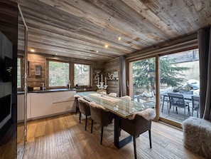 A wooden cabin interior with a dining area, large windows, and a view of the outdoors. - Chalet-Nashira-Deluxe-Private Bathroom-Terrace (Bolquère)