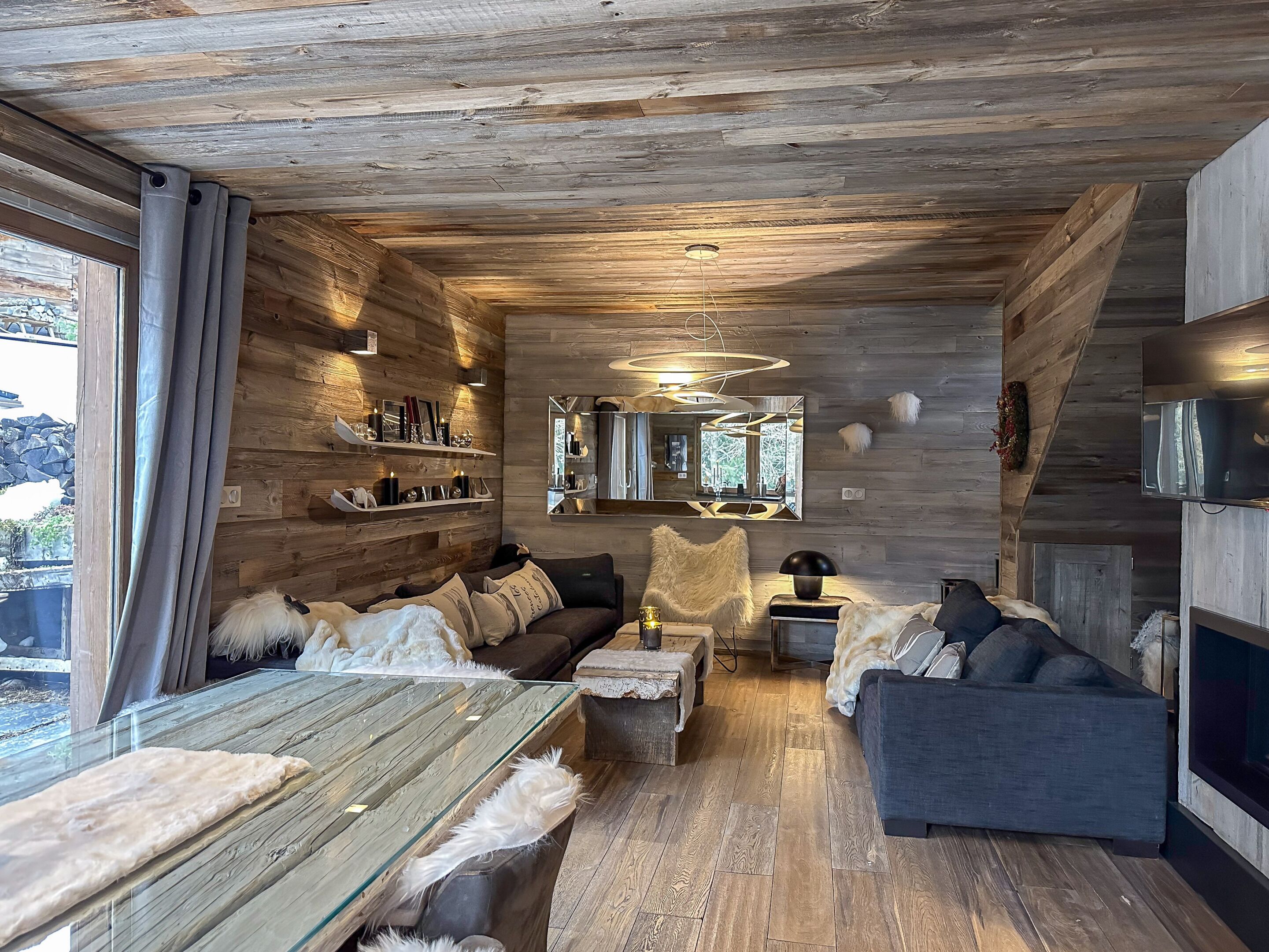 L’intérieur d’un chalet accueillant, avec des murs en bois, un canapé, une table basse et une cheminée.