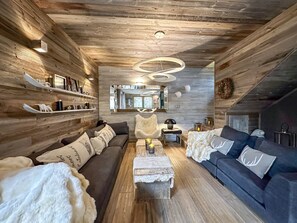A cozy, log-furnished living room with a sofa, a coffee table, and a fireplace.