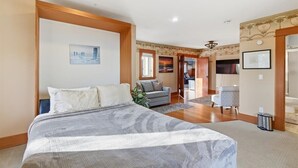 Een slaapkamer met een groot bed, een bank en een stoel. Er is een gang naar een badkamer.