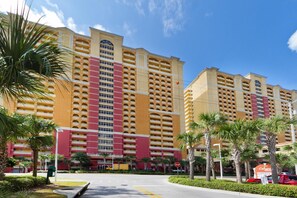 Ein mehrstöckiges Hotel mit Balkonen, Palmen und einem Stoppschild.