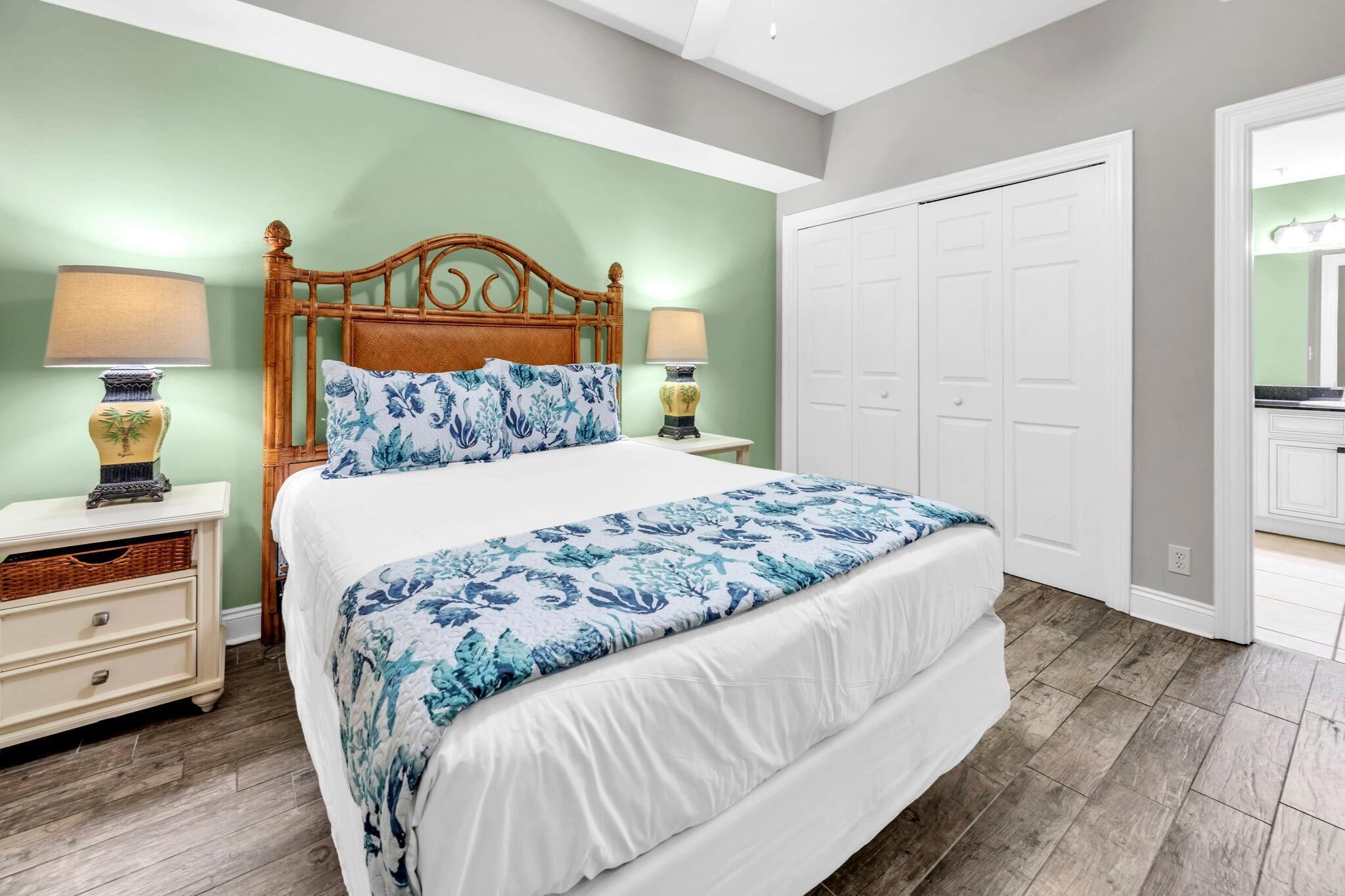 A bedroom with a bed, nightstands, a lamp, a dresser, and a closet.