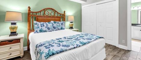 A bedroom with a bed, nightstands, a lamp, a dresser, and a closet.