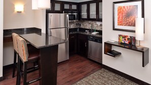 Una cocina moderna con armarios de madera oscura, electrodomésticos de acero inoxidable y una barra con taburetes.