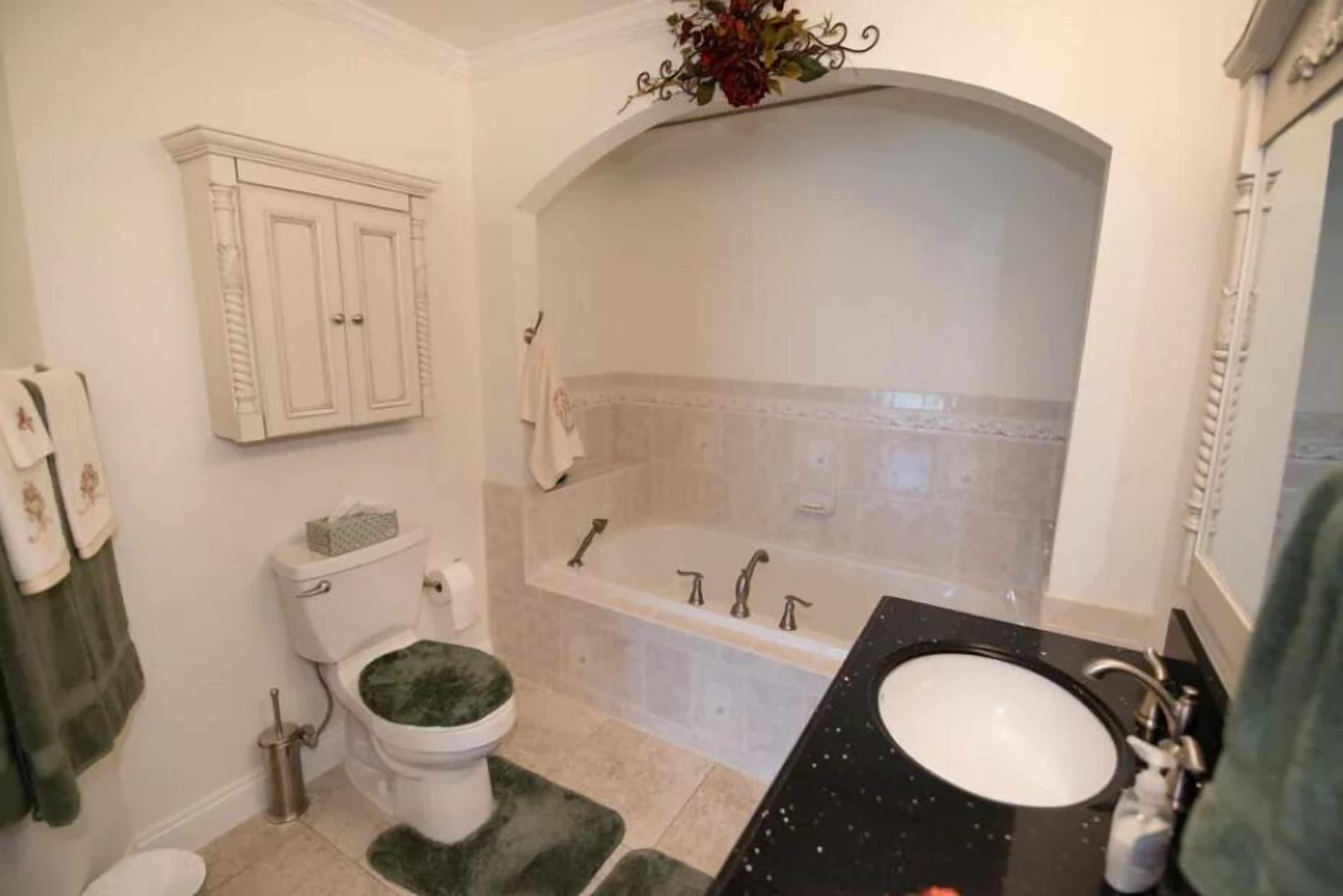 A bathroom with a toilet, sink, bathtub, and a cabinet.