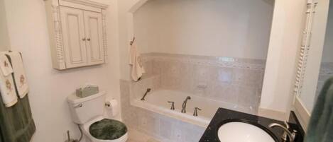 A bathroom with a toilet, sink, bathtub, and a cabinet.