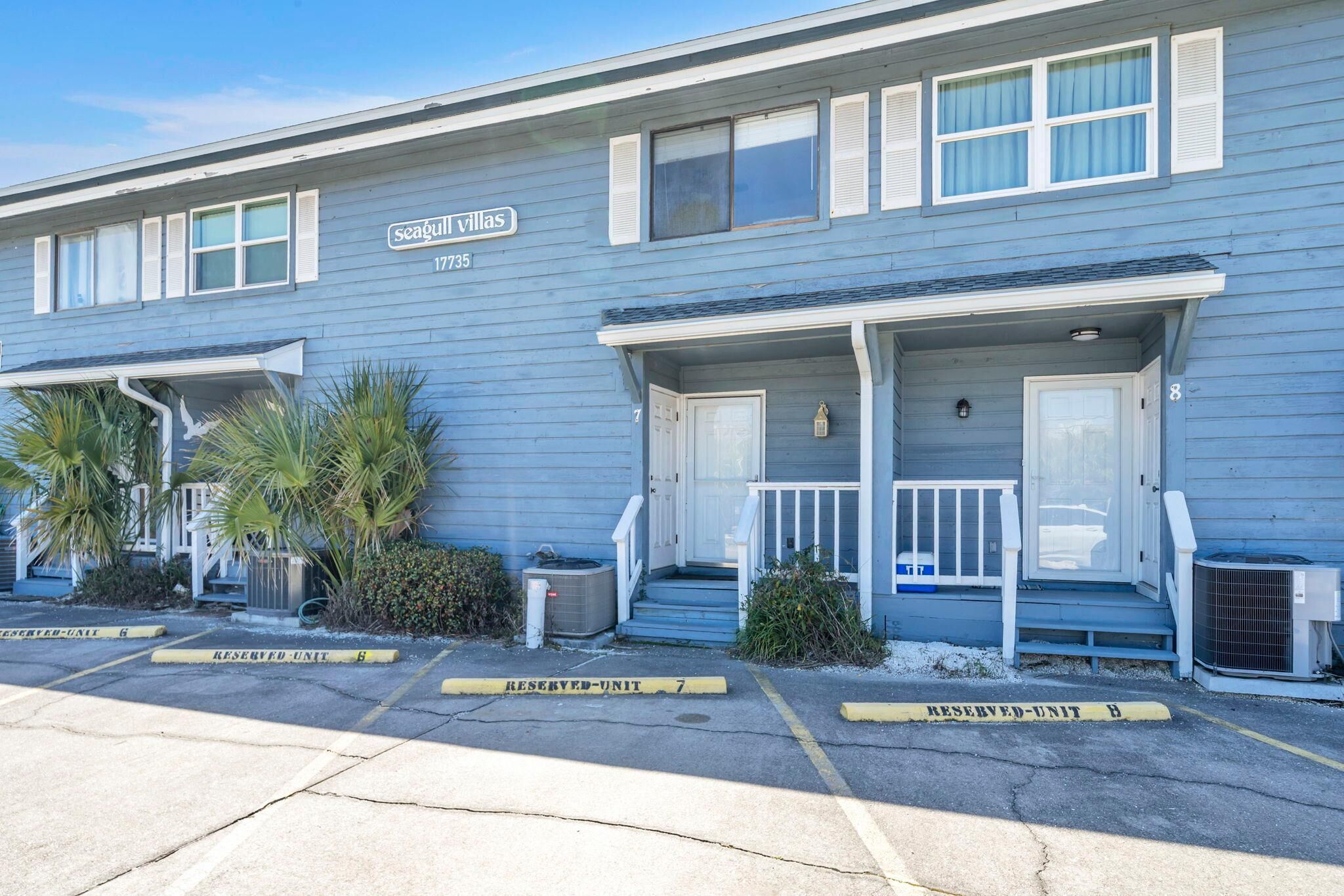 A two-story building with a sign reading "Seagull Villas" and the number 1735. There are two front porches with steps leading to the doors.