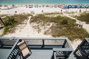 Blick auf einen Strand mit einer Holzterrasse und Liegestühlen.