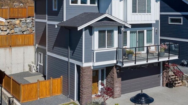 A two-story house with a balcony, stone foundation, and a garage.