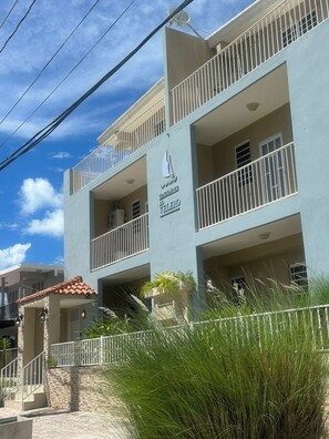 A multi-story building with balconies, a sign indicating it's a condominium, and a clear sky.