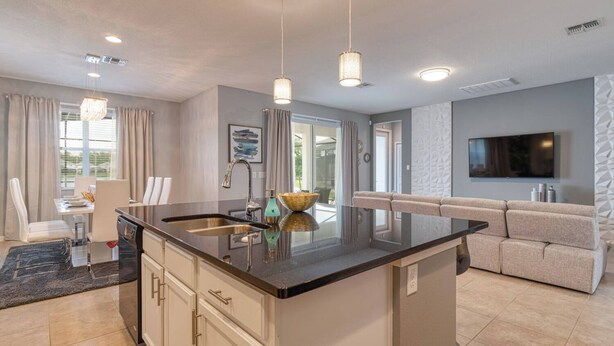A modern kitchen with a central island, pendant lighting, and a dining area with a table and chairs.