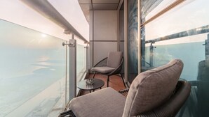 Un balcon avec vue sur l’eau, une chaise et une petite table.