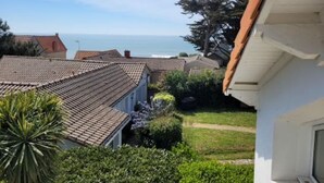 Un quartier résidentiel caractérisé par des toits recouverts de tuiles en terre cuite, une vue dégagée sur la mer et une pelouse bien entretenue.