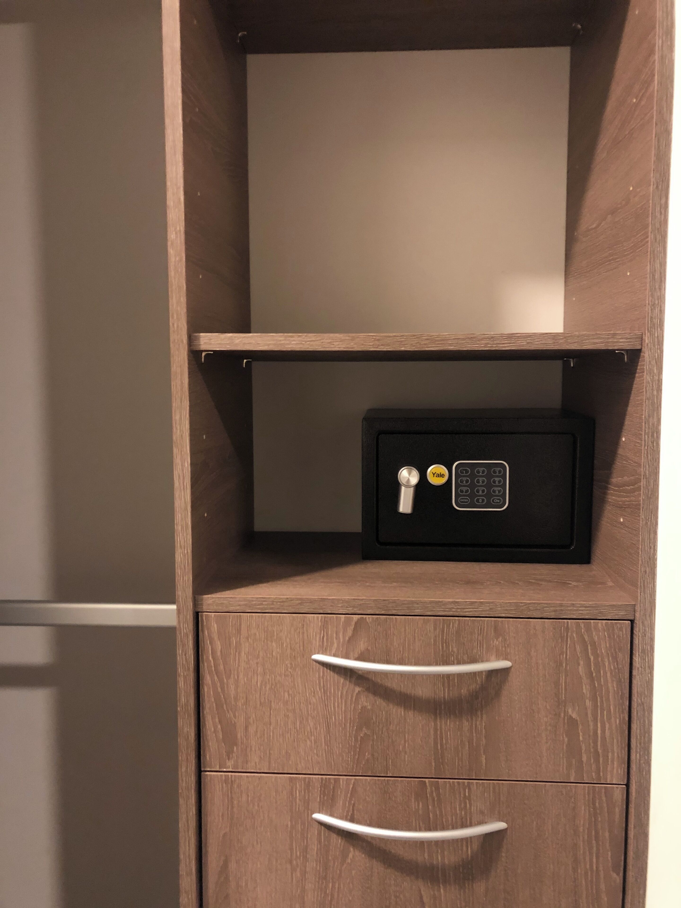 A wooden cabinet with a Yale safe and two drawers.