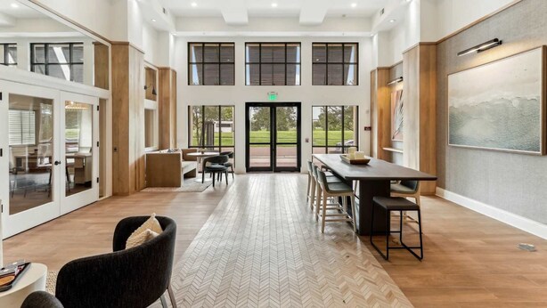 Ein großzügiges, modernes Interieur mit einem geräumigen Essbereich, verschiedenen Sitzgelegenheiten und großen Fenstern mit Blick ins Freie.