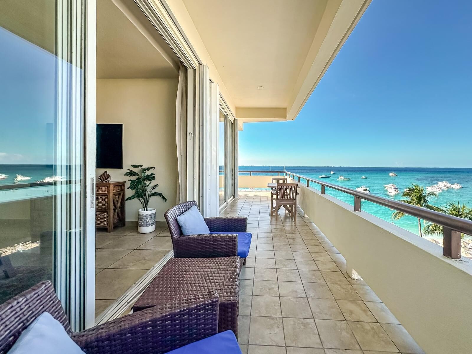 A balcony with wicker furniture, a potted plant, and a view of the ocean.