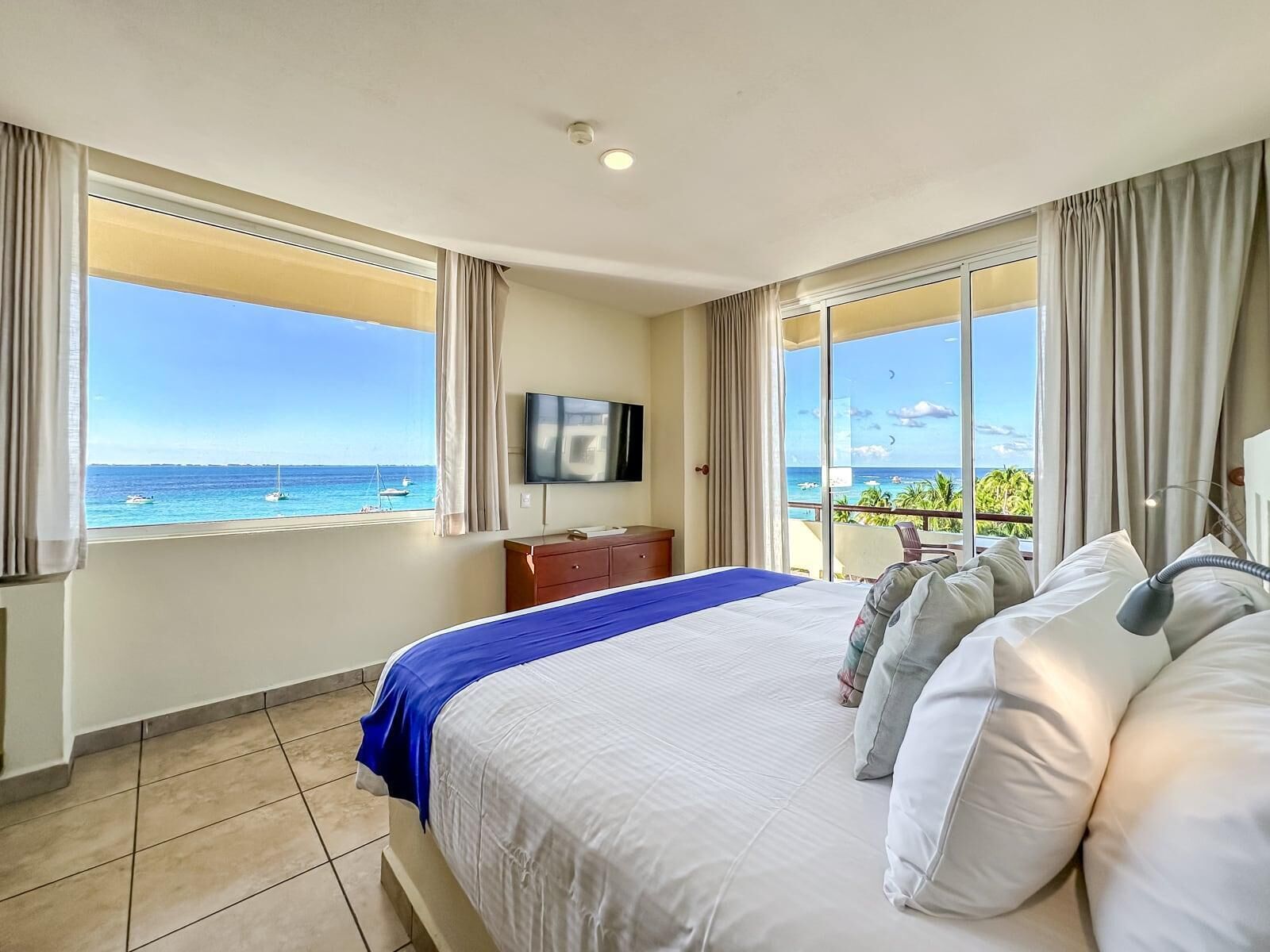 Habitación de hotel con una cama grande, televisión y balcón con vista al océano.