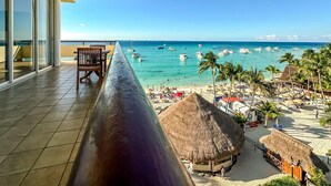 Un balcon avec vue sur une plage, des palmiers et des bateaux.