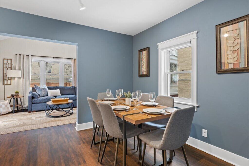 A dining area with a wooden table set for four, surrounded by grey chairs.