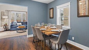 Un coin repas avec une table en bois dressée pour quatre personnes, entourée de chaises grises.