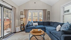 Un salon comprenant un canapé d’angle, une table basse et une vue dégagée grâce à de grandes fenêtres.