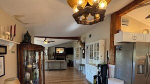 Una cocina amplia con un refrigerador moderno, armarios de madera y un candelabro.